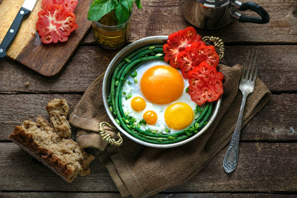 istock Sunny side fried eggs in a copper pan with tomatoes and green beans, copy space. 1178624382