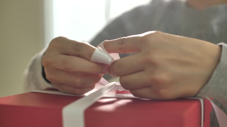 Gift wrapping. woman tie a White ribbon bow