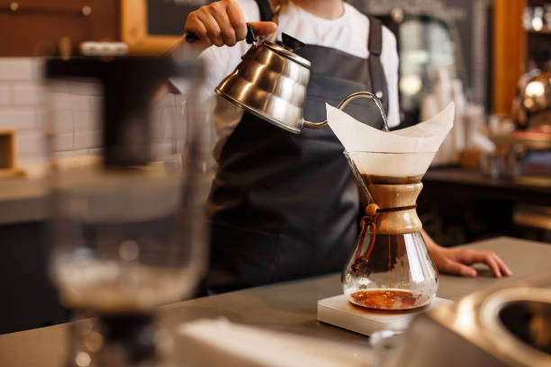 Professional barista preparing coffee using glass coffeemaker pour over coffee maker and drip kettle. Professional barista preparing coffee using glass coffeemaker pour over coffee maker and drip kettle. Young woman making coffee. Alternative ways of brewing coffee. Coffee shop concept. barista stock pictures, royalty-free photos & images