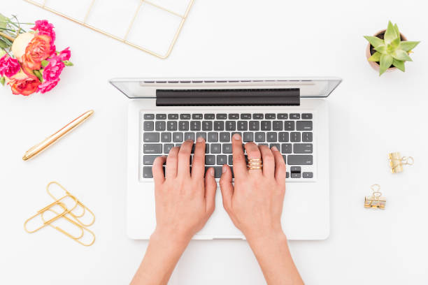 A woman working at a laptop on a desk. Conveys the idea of a blogger or influencer working from home.