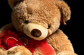 A large valentine holiday teddy bear on a black background. Close up. .