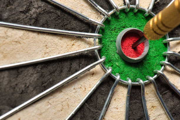 un dardo colpisce il centro della tavola da freccette noto anche come "occhio di toro". - target dartboard bulls eye dart foto e immagini stock