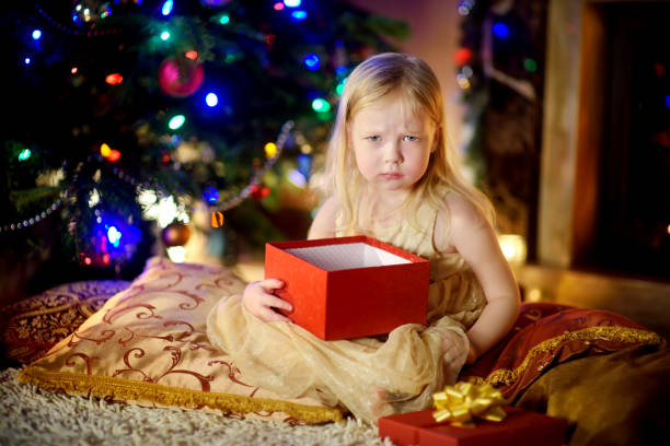 la petite fille mignonne est malheureuse avec son cadeau de noel - holiday emotional stress christmas santa claus photos et images de collection