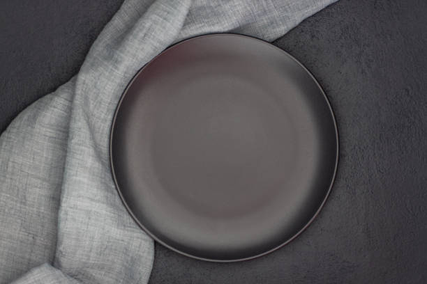 istock Black plate, cutlery and napkin on stone table top view. Table setting. 1178674231