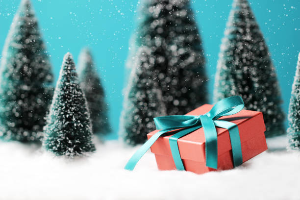 istock Christmas background with red gift box and blurred Christmas trees on table. 1178679160