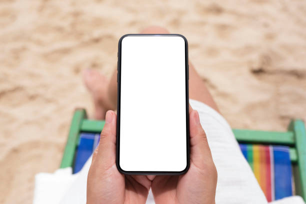 istock a woman holding black mobile phone with blank desktop screen while sitting on a beach chair 1178681800