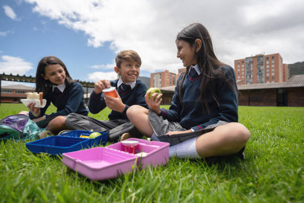 grupo de estudiantes en la escuela comiendo su merienda en su descanso - lunch box child education school fotografías e imágenes de stock