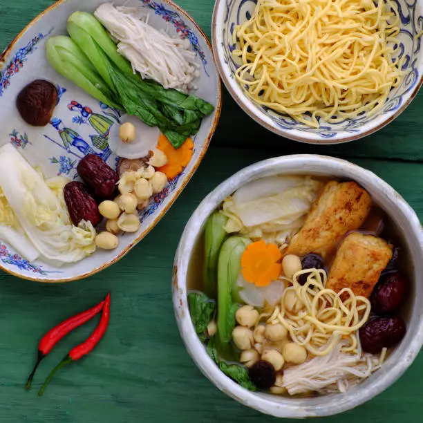 Top view Vietnamese vegan noodle soup for breakfast, vegetarian homemade food from tofu, jujube fruit, lotus seed, bok choy, mushroom, spice, healthy dish with vegetables ingredient