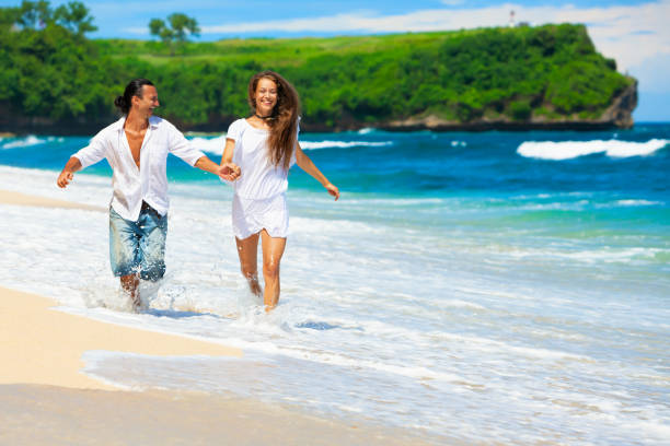 istock Young couple run by white sand beach along sea surf 1178702198