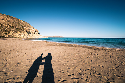 Shadows of young couple holding hands on Playa del Plomo (Andalusia, Spain).