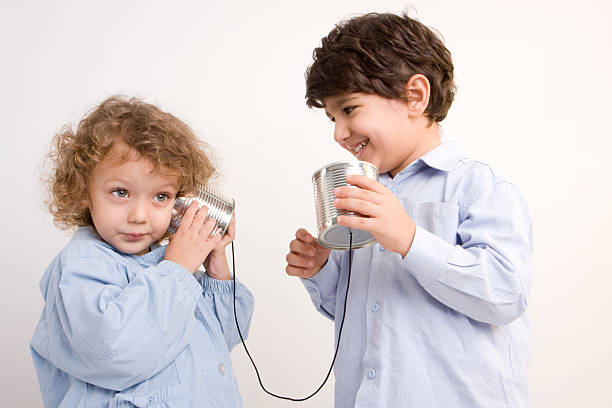 маленькая девочка и мальчик связь через телефон из консервных банок - telephone can communication tin can phone стоковые фото и изображения