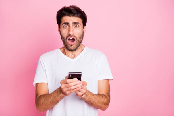 istock Portrait of negative addicted shocked funky middle eastern man hold use smartphone read got notification dislike scream omg unbelievable expression wear style clothes isolated pastel color background 1178712242