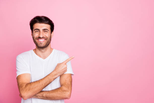 istock Portrait of positive cheerful cool middle eastern man point index finger copy space indicate ads discounts wear white clothes isolated over pink color background 1178713112