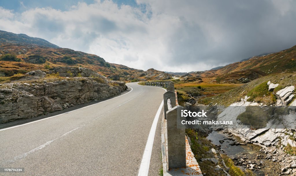two-lane road leading over a high remote and wild mountain pass in the Swiss Alps A two-lane road leading over a high remote and wild mountain pass in the Swiss Alps Narrow Stock Photo