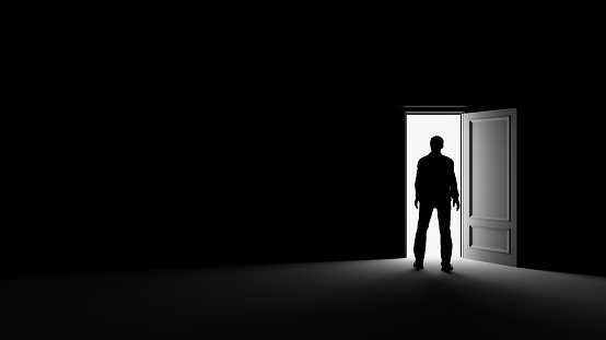 Silhouette of a man standing in a dark room lit by bright light. 3d rendering