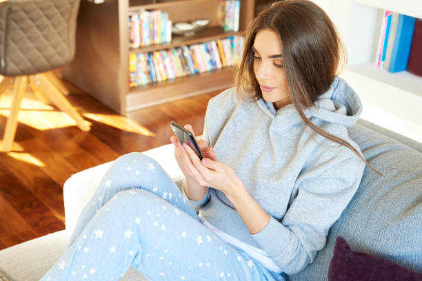 istock Beautiful young woman text messaging while sitting on sofa at home 1178722237