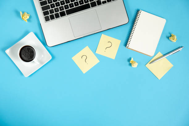 istock Question mark on sticky notes, notebook, cup coffee, laptop and pen on blue background. FAQ concept. Working with clients. Troubles in work. Flat lay, top view, copy space 1178722373