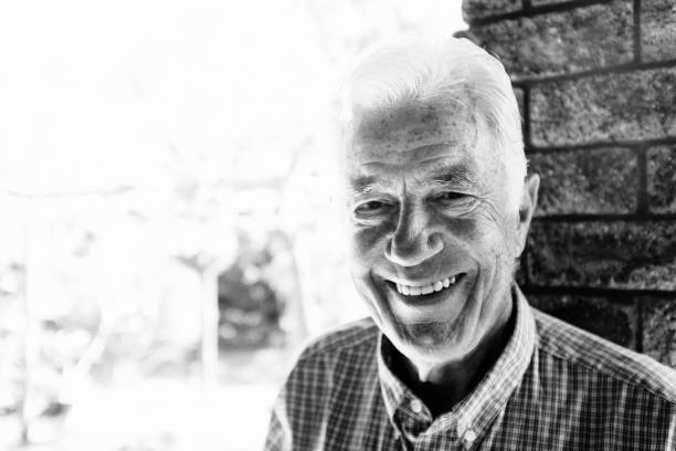 istock Cheerfully smiling senior man standing outdoors by brick wall 1178722391