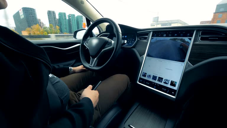 A man is sitting in a vehicle which is being automatically driven