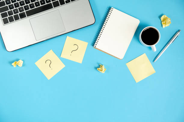 istock Question mark on sticky notes, notebook, cup coffee, laptop and pen on blue background. FAQ concept. Working with clients. Troubles in work. Flat lay, top view, copy space 1178725375