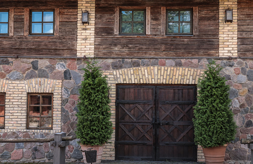 Fragment of a stone wall of a barn with a wooden superstructure and a forged barn door