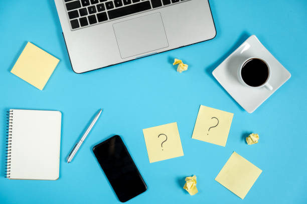 istock Question mark on sticky notes, notebook, laptop, cup coffee, phone, pen on blue background. FAQ concept. Working with clients. Troubles in work. Flat lay, top view, copy space 1178726854