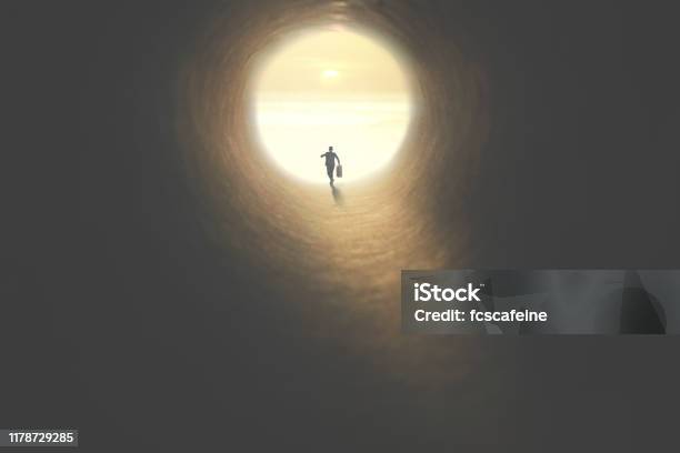 Man With Suitcase Running To The Exit Of A Tunnel Illuminated Of The Sun Stock Photo - Download Image Now