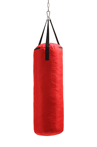 Studio shot of a red punching bag hanging isolated on white background