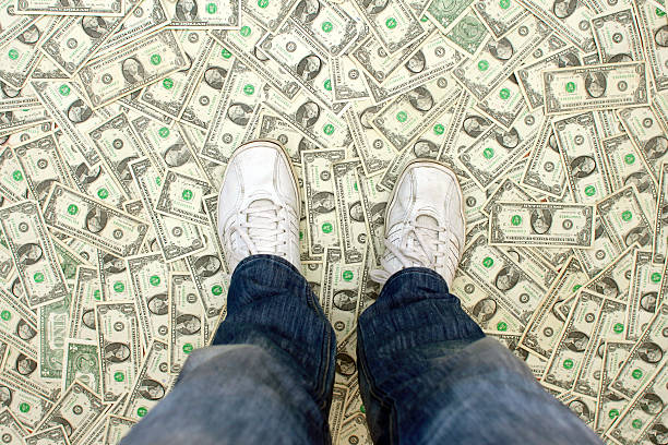 Found Money: Man Standing on a Floor of Dollar Bills  running shoes on floor stock pictures, royalty-free photos & images