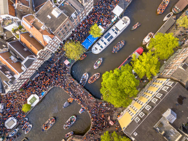 Canal boat parade on Koningsdag Kings day festivities in Amsterdam. Birthday of the king. Seen from helicopter.