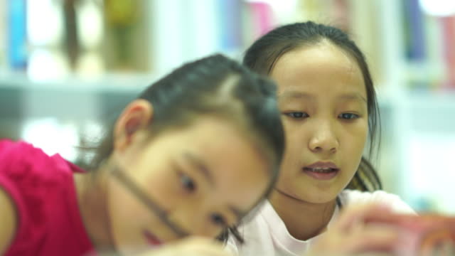 Two Asian girls e-learning together from smartphone
