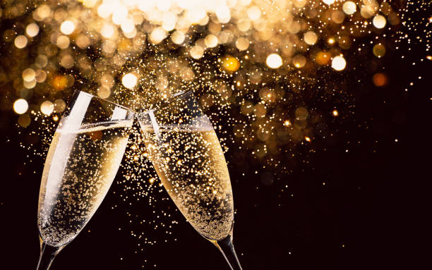 Celebration toast with champagne Two glasses of champagne toasting in the nigh with lights bokeh, glitter and sparks on the background two objects photos stock pictures, royalty-free photos & images