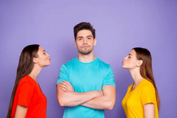 Photo of Photo of proud self-confident modern hipster in blue outfit choosing the lady to kiss standing with folded crossed arms isolated violet purple background