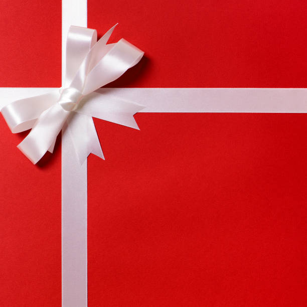 istock White ribbon bow, red gift wrap paper background, copy space, vertical 1178742559