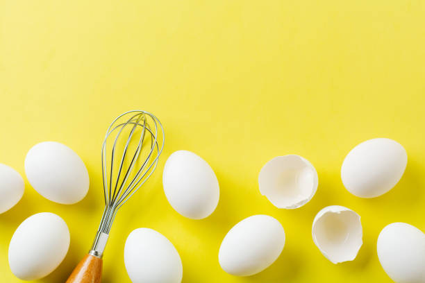 istock White raw chicken eggs lying in horizontal row with broken egg on yellow background. Top view. 1178743899