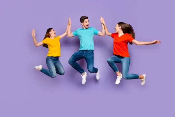 Full length body size photo of three excited glad optimistic delightful millennial generation, group in blue yellow outfit having fun and good mood isolated violet background