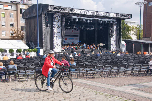 bici da donna oltre una prova d'orchestra a dortmund-stadtgarten friedensplatz (piazza della pace), germania - editorial urban scene horizontal people foto e immagini stock