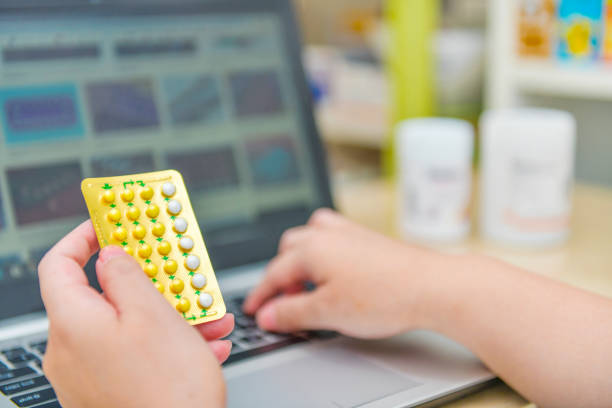 istock Pharmacist using the computer laptop Hand holding birth control pills in drug store. 1178752173