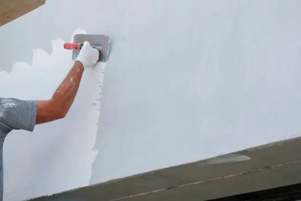 Painter applying fresh paint on the house facade