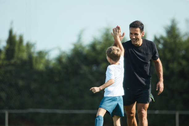 fußball-trainer high-fives seine spieler nach einer trainingsübung. - soccer child coach childhood stock-fotos und bilder