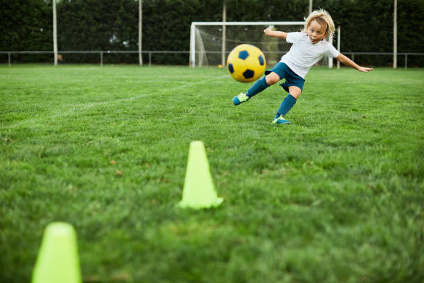 i bambini piccoli sparano un calcio perfetto. - tirare in rete foto e immagini stock