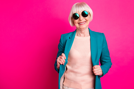 Portrait of her she nice-looking attractive cheerful cheery gray-haired lady wearing, blue green jacket enjoying life lifestyle isolated on bright vivid shine vibrant pink fuchsia color background