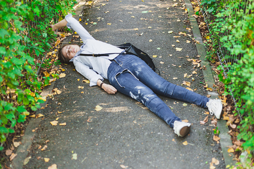 Young woman suffering from epilepsy fainted in the middle of the street - Sick girl fallen injured on the ground after seizure caused by diseases or stress