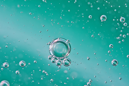 Bubbles of oxygen or air in liquid. Macro. Oxygen bubbles in water, turquoise background, concept of ecology, purity and other related to liquid or water.