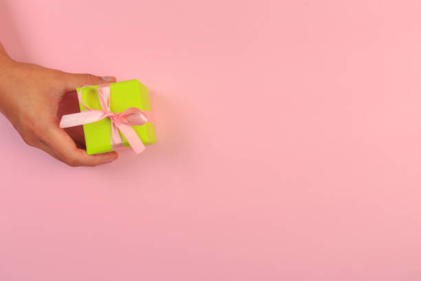 istock gift in female hands on a colored background top view. 1178760208