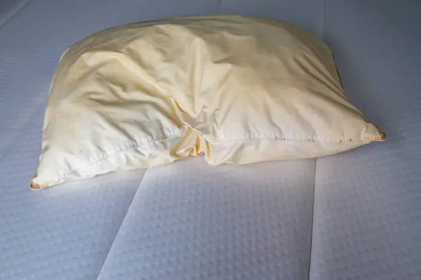 Photo of Dirty stained pillow on new white bed, Close up shot, Selective focus, Bedroom cleaning concept