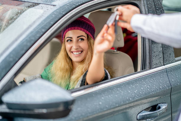 young woman take the key from valet to drive her car - valet parking imagens e fotografias de stock