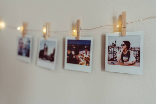 Instant photo prints hanging on string at white wall