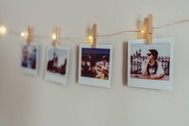 Instant photo prints hanging on string at white wall Instant print photos in a row string photos stock pictures, royalty-free photos & images