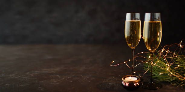 Champagne on old dark stone plate Two glasses of champagne on old dark stone plate and christmas decoration gala dinner table stock pictures, royalty-free photos & images